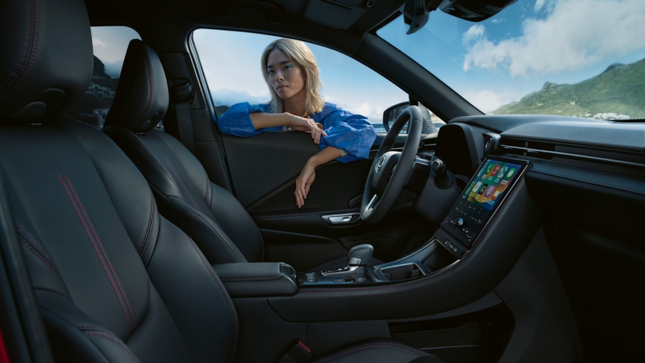 Een persoon staat voor het raam van een Lexus LBX
