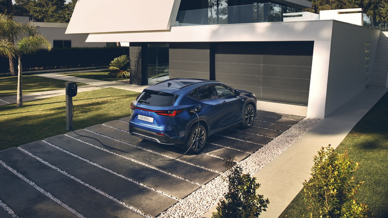 Een Lexus NX 450h+ aangesloten op een laadstation buiten een woning