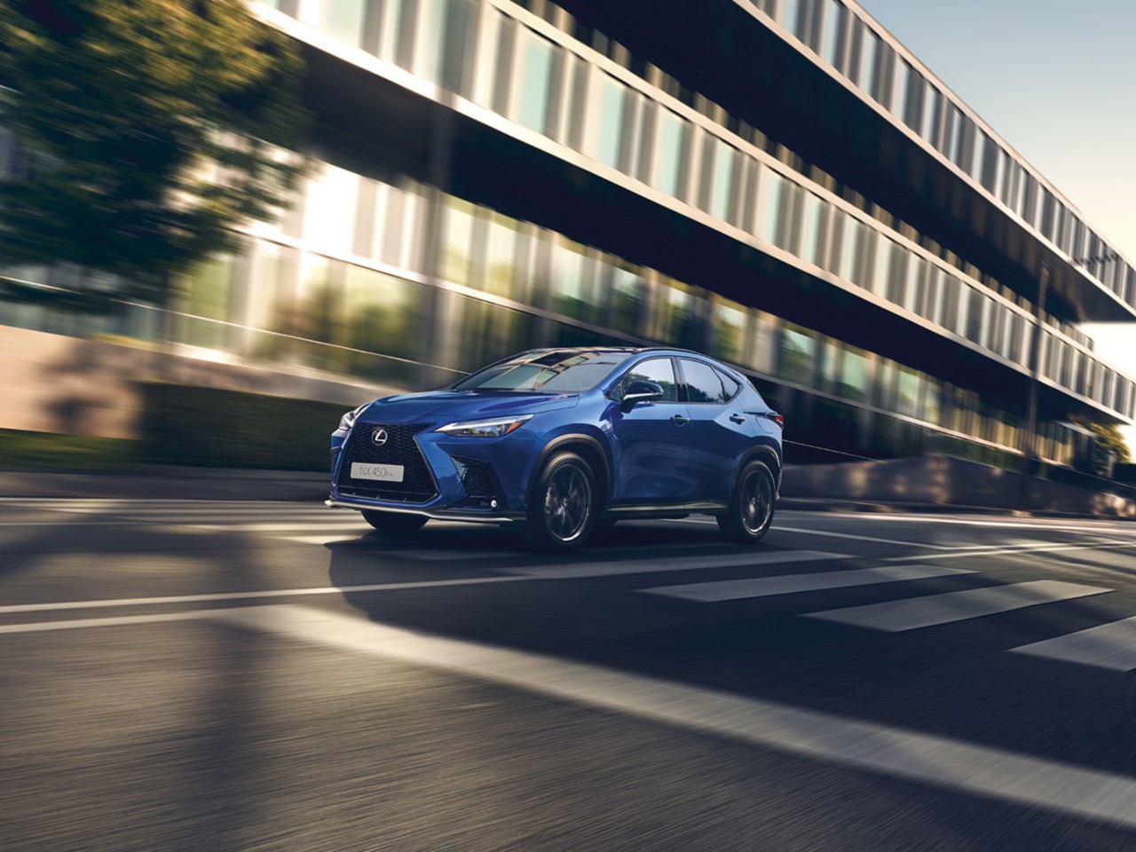 Een blauwe Lexus NX 450h+ rijdend op een weg