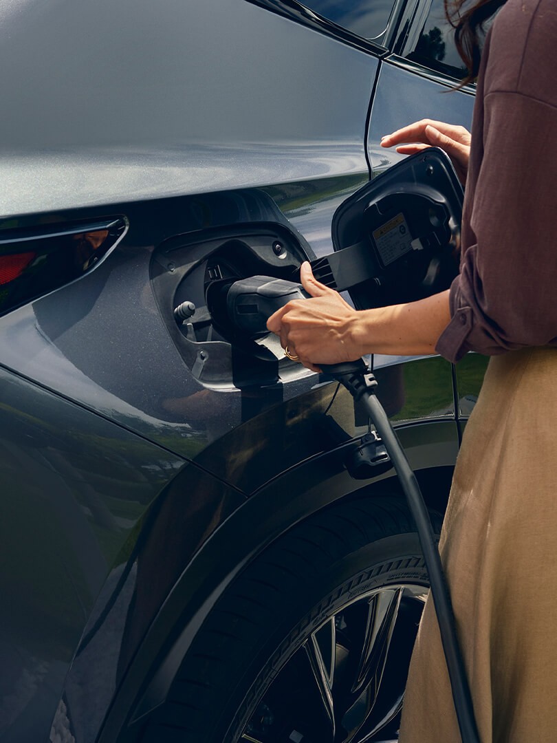 Een vrouw sluit een oplader aan op een Lexus NX 