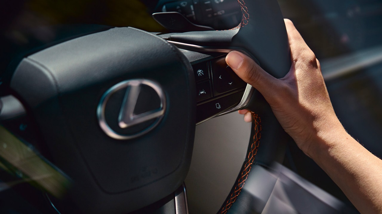 Een persoon met zijn hand op een Lexus stuurwiel